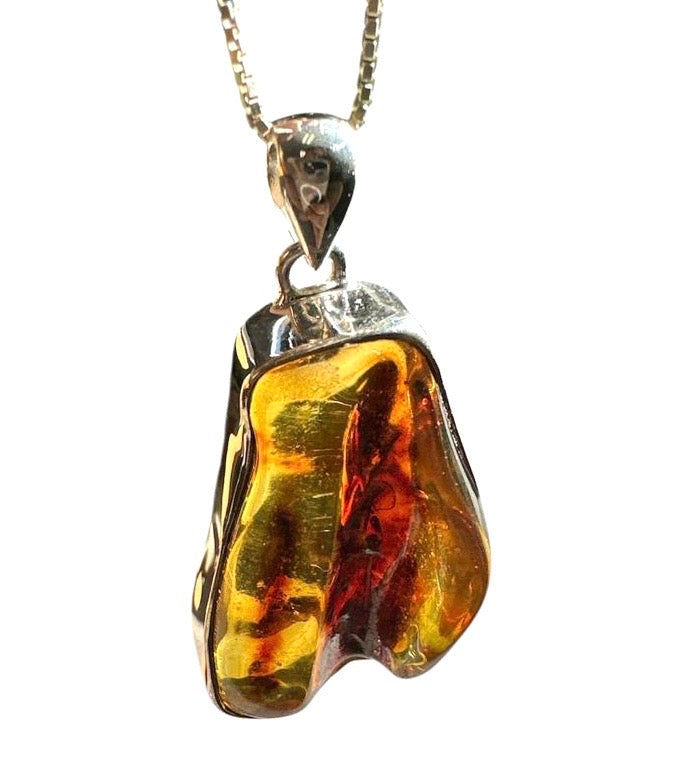 Amber pendant on a gold chain against a white background